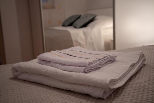 een stapel handdoeken zittend op een bed voor een spiegel bij Viollet in Omiš