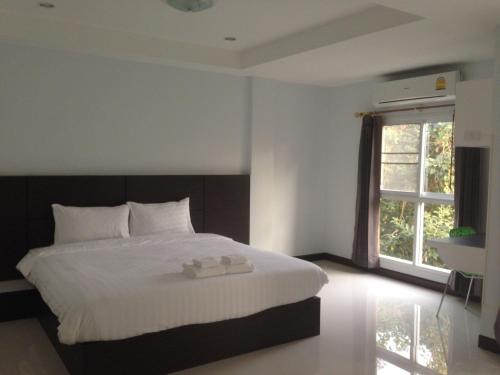 a bedroom with a large white bed with a window at Praiyanan Place Hotel in Maha Sarakham