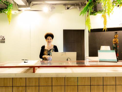 a woman standing in an office with a laptop at Khao San Social Capsule Hostel in Bangkok