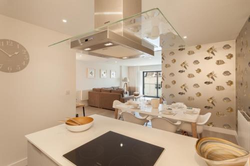 a kitchen and living room with a table and a dining room at 12 Woolacombe East - Luxury Apartment at Byron Woolacombe, only 4 minute walk to Woolacombe Beach! in Woolacombe