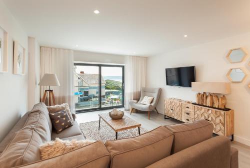 a living room with a couch and a tv at 12 Woolacombe East - Luxury Apartment at Byron Woolacombe, only 4 minute walk to Woolacombe Beach! in Woolacombe