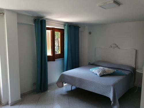 a bedroom with a bed with blue curtains and a window at Scrusciu do Mari in Butera