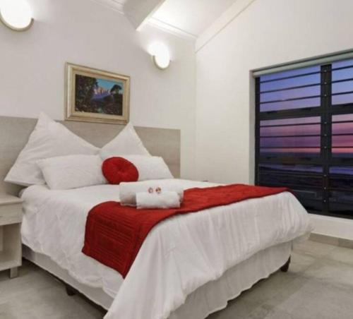 1 dormitorio con 1 cama grande con manta roja en Pearl Haven, beach house with magnificent views!, en Yzerfontein