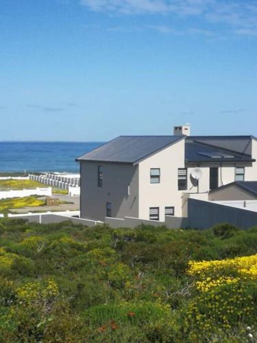 a building on the beach with the ocean in the background at Pearl Haven, coastal comfort just steps from the shore! in Yzerfontein