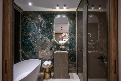 a bathroom with a tub and a sink and a mirror at Happy Cretan Suites in Agia Pelagia