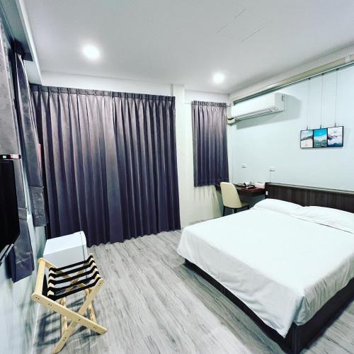 a bedroom with a bed and a chair and a desk at ChaoChaoINN in Chaozhou