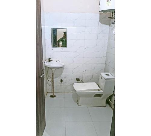 a white bathroom with a toilet and a sink at Hotel 7 Spices Restaurant & Banquet By WB Inn in Agra