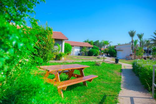 a wooden picnic table sitting in the grass at Agamim Hotel Ashkelon in Ashqelon