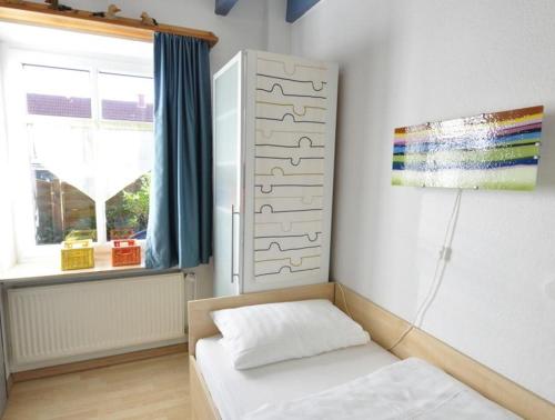 Kleines Zimmer mit einem Bett und einem Fenster in der Unterkunft Huus vör d Diek Wohnung 1 in Neuharlingersiel