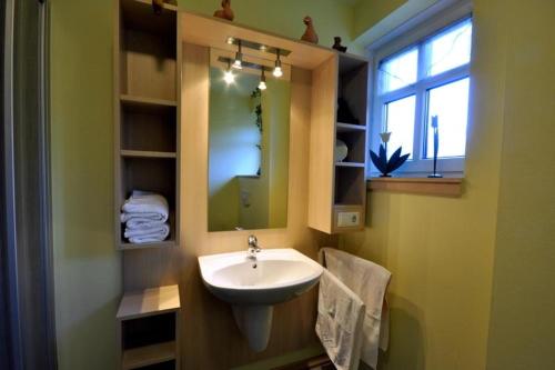 ein Bad mit einem Waschbecken, einem Spiegel und einem Fenster in der Unterkunft Huus vör d Diek Wohnung 1 in Neuharlingersiel