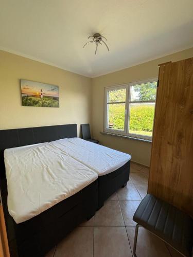 a bedroom with a large bed and two windows at Ferienbungalow Zum Anleger 3 in Hohenkirchen