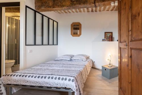 a white bedroom with a bed and a bathroom at Lou Baoumoun in Coursegoules