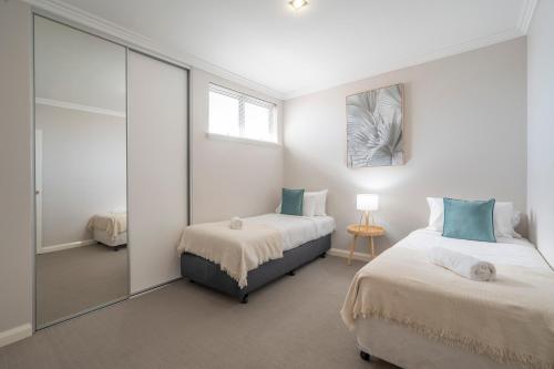 sypialnia z 2 łóżkami i lustrem w obiekcie 30 Rich On Richmond Modern Family Home 6 w mieście Perth