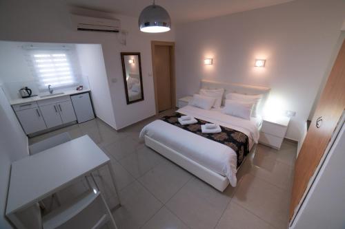a bedroom with a large white bed and a sink at Agamim Hotel Ashkelon in Ashqelon