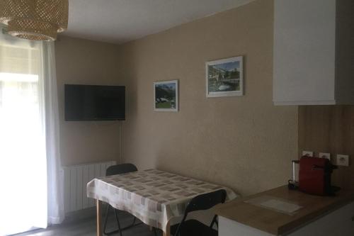 une salle à manger avec une table et une télévision au mur dans l'établissement La Moulinière 1 - Functional and well-equipped studio, à Névache