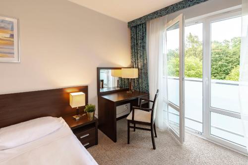 a hotel room with a bed and a desk and a window at VacationClub – Aquarius Apartament 99 in Kołobrzeg