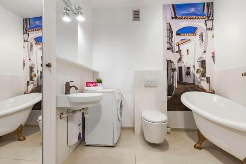 a bathroom with a sink and a tub and a toilet at VacationClub - Plażowa 7 Apartament 2 in Gąski