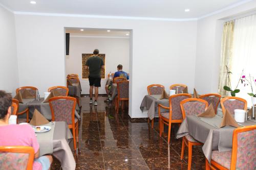 a man walking through a room with tables and chairs at Hotel Sofia in Bad Wildungen