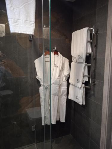 a shower stall with white robes and towels at Hotel Zefir in Drohobytsch