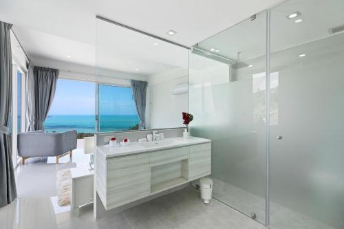 ein weißes Bad mit einem Waschbecken und einer Dusche in der Unterkunft Villa The Wave in Nathon Bay