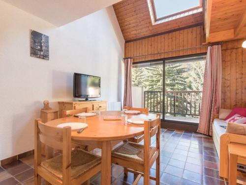 une salle à manger avec une table en bois et une télévision dans l'établissement Duplex 6 pers avec mezzanine et parking à Serre-Chevalier, Saint-Chaffrey - FR-1-330E-27, à Saint-Chaffrey