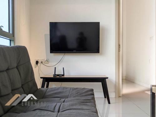 a living room with a couch and a tv on a wall at Marina Times Square Homestay by Evernent in Miri
