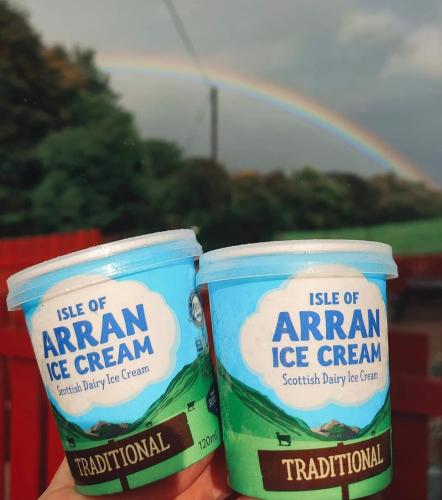 two containers of ice cream with a rainbow in the background at The Old Dairy in Brodick