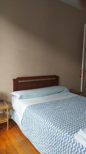 a bed with a blue and white comforter in a bedroom at Pensión Manoli in Bilbao
