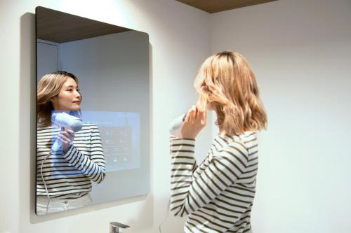 a woman brushing her hair in front of a mirror at Prince Smart Inn Ebisu in Tokyo