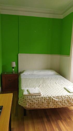 a green bedroom with a bed with a green wall at Pensión Manoli in Bilbao