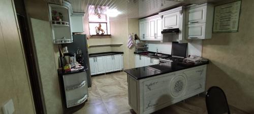 a kitchen with white cabinets and a black counter top at Aminabonu Hotel in Samarkand