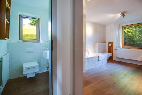 a bathroom with a tub and a toilet and a sink at Künstlervilla mit grandiosem Panoramablick in Fischbachau