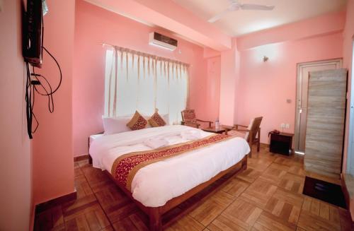 - une chambre avec des murs roses et un grand lit dans l'établissement Hotel Peace Stupa, à Pokhara