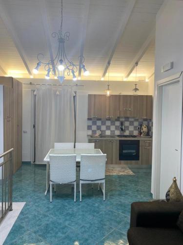 a dining room with a table and chairs and a kitchen at Le Quattro Perle in Terrasini