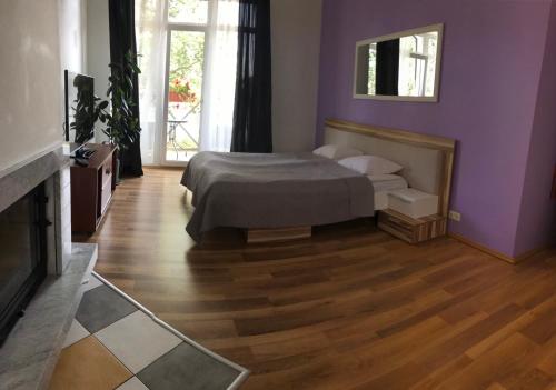 een slaapkamer met paarse muren, een bed en een open haard bij Lilaste.eu in Lilaste