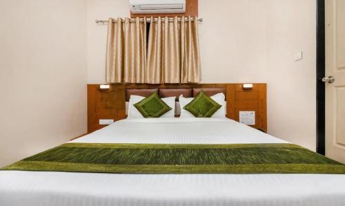 a bedroom with a white bed with green pillows at Hotel Volga Plaza in Mumbai