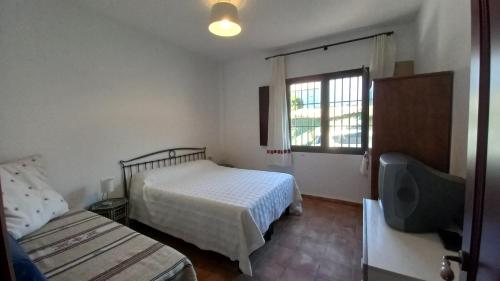 a bedroom with a bed and a tv and a window at Casa Aldea de la Corte 