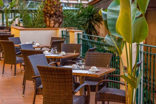 an empty restaurant with tables and chairs and a plant at Valentin Son Bou in Son Bou