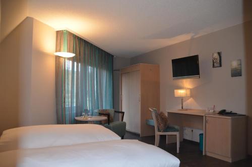 a hotel room with two beds and a table and a desk at Castell Hotel & Restaurant in Leinsweiler
