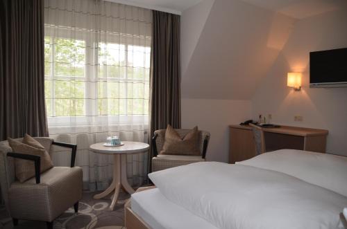 a hotel room with a bed and a table and chairs at Castell Hotel & Restaurant in Leinsweiler