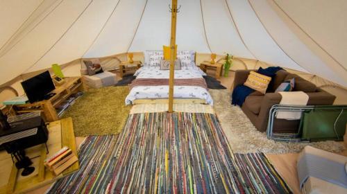 a room with a tent with a bed and a couch at Ffos Wilkin Glamping & Alpacas in Kidwelly