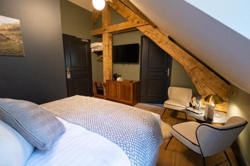 um quarto com uma cama e uma cadeira e uma televisão em Hôtel du cirque et de la cascade em Gavarnie
