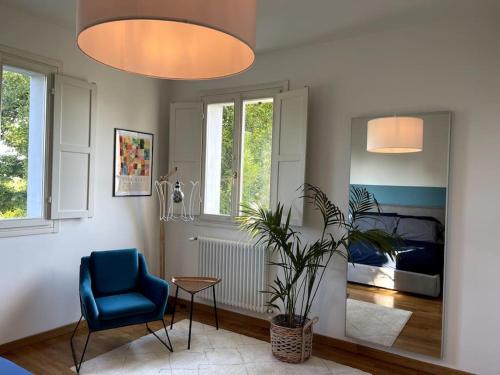 a living room with a blue chair and a bedroom at Appartamento moderno in Tenuta Melloni in Anzola dell'Emilia