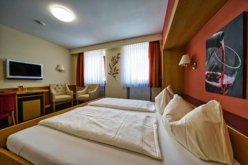 a hotel room with two beds and a desk at Hotel Tenner in Neustadt an der Weinstraße