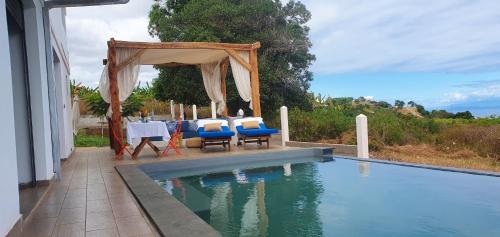 a swimming pool with a tent and chairs next to a house at Villa Vintana Nosy Be in Nosy Be