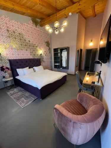 a bedroom with a bed and a chair at Pensiunea Casa Buna in Gîrbova