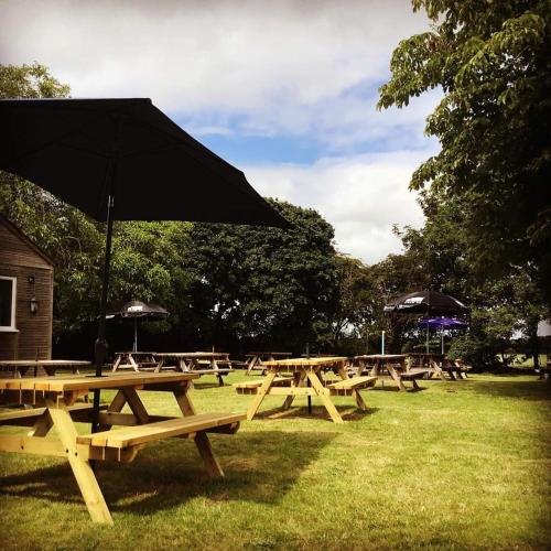 um grupo de mesas de piquenique com guarda-chuva em Five Bells Wickham em Newbury