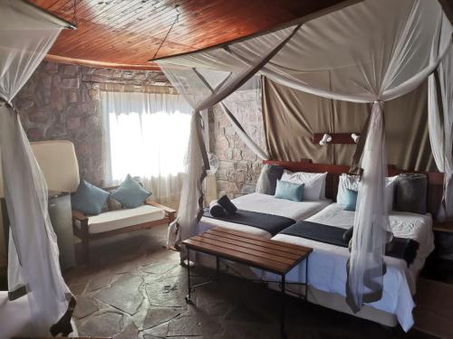 a bedroom with a canopy bed and a couch at Little Sossus Lodge in Sesriem