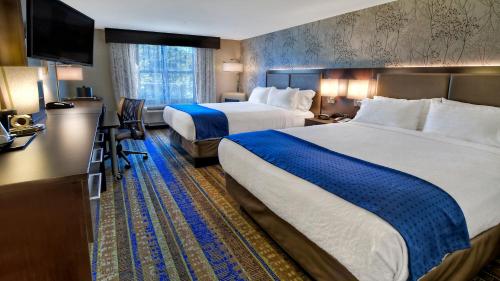 a hotel room with two beds and a flat screen tv at Holiday Inn & Suites Tupelo North, an IHG Hotel in Tupelo