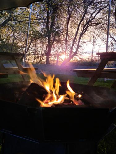 een vuurplaats in een park met de zonsondergang op de achtergrond bij Five Bells Wickham in Newbury
